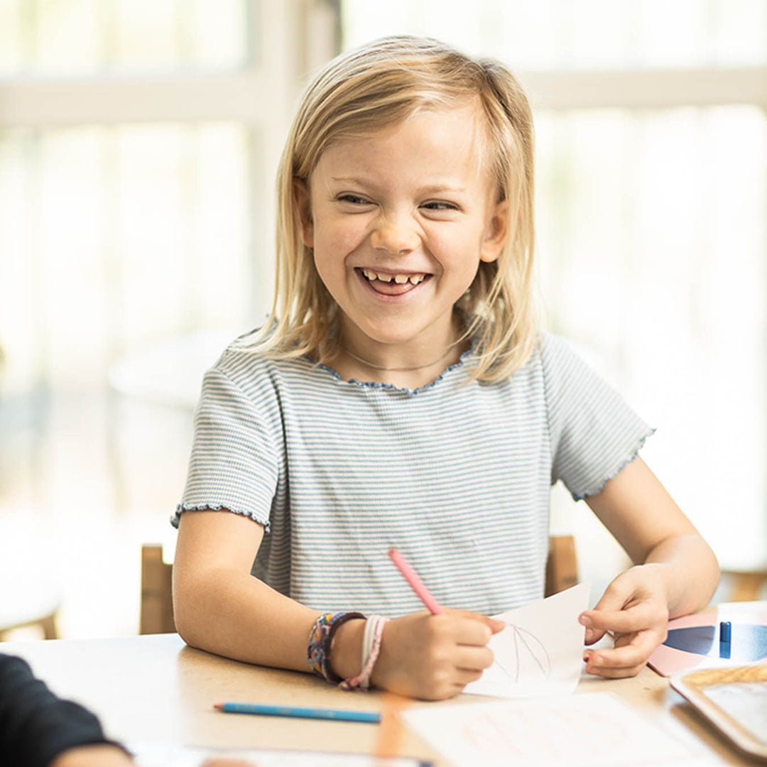 En elev sitter vid en skolbänk och ritar.