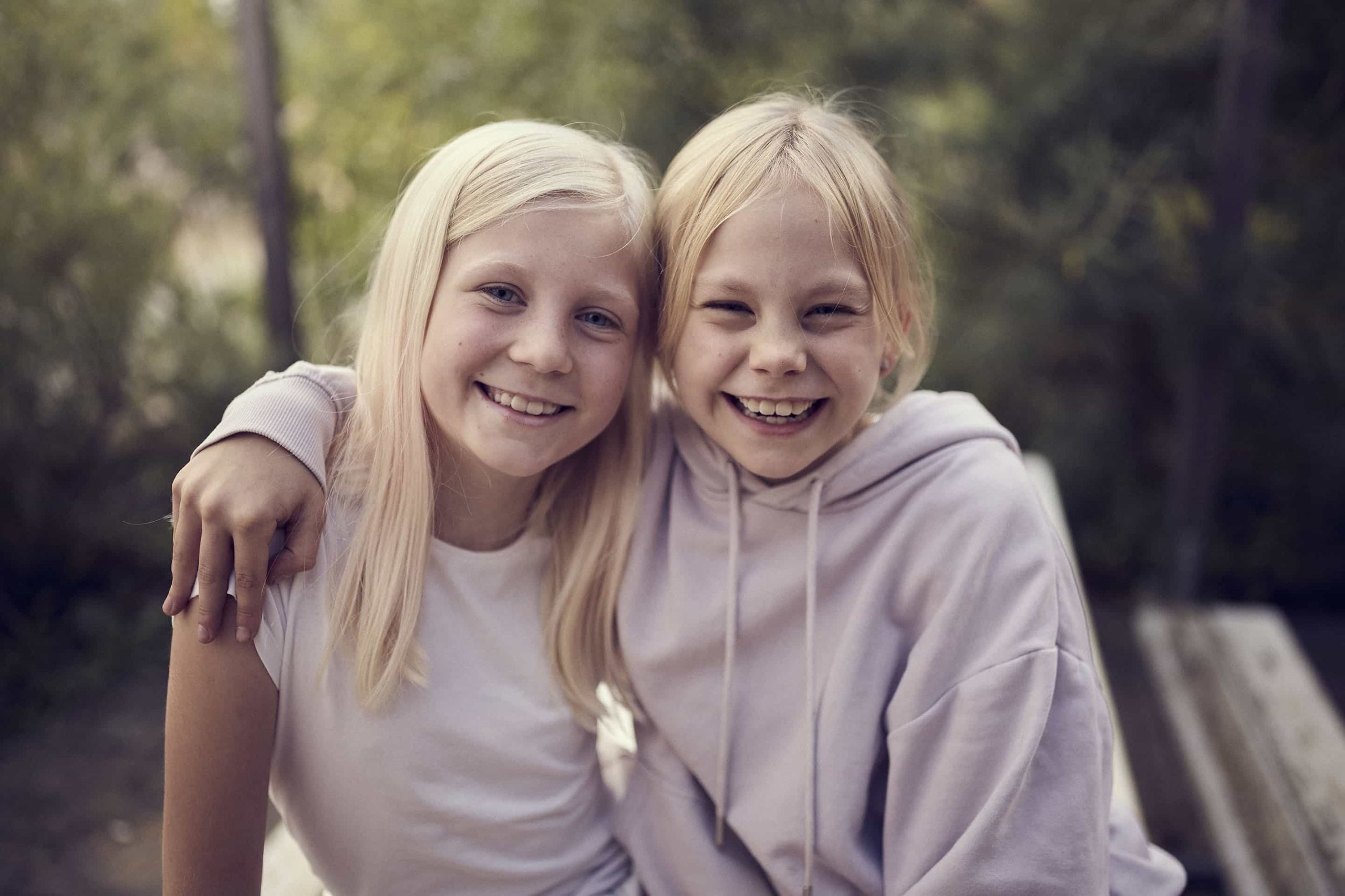 Två elever på Montessori Mondial sitter utomhus, håller om varandra och ser glada ut,