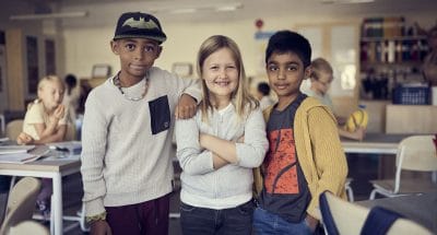 Tre elever står bredvid varandra i ett klassrum på Montessori Mondial.