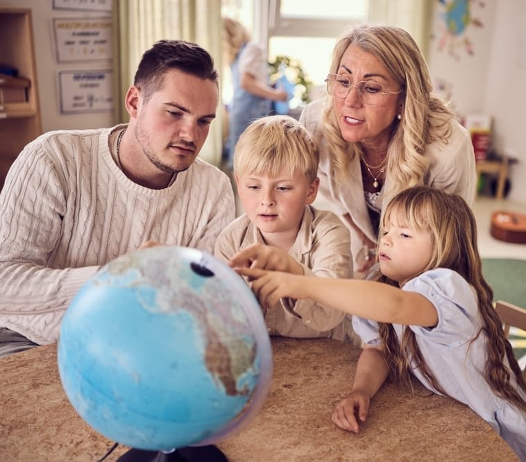 Två elever och pedagoger kollar på en jordglob tillsammans.
