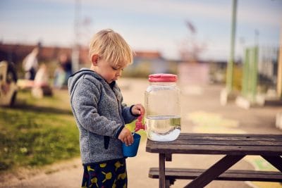 Barn på förskolan tappar upp vatten i ett glas.