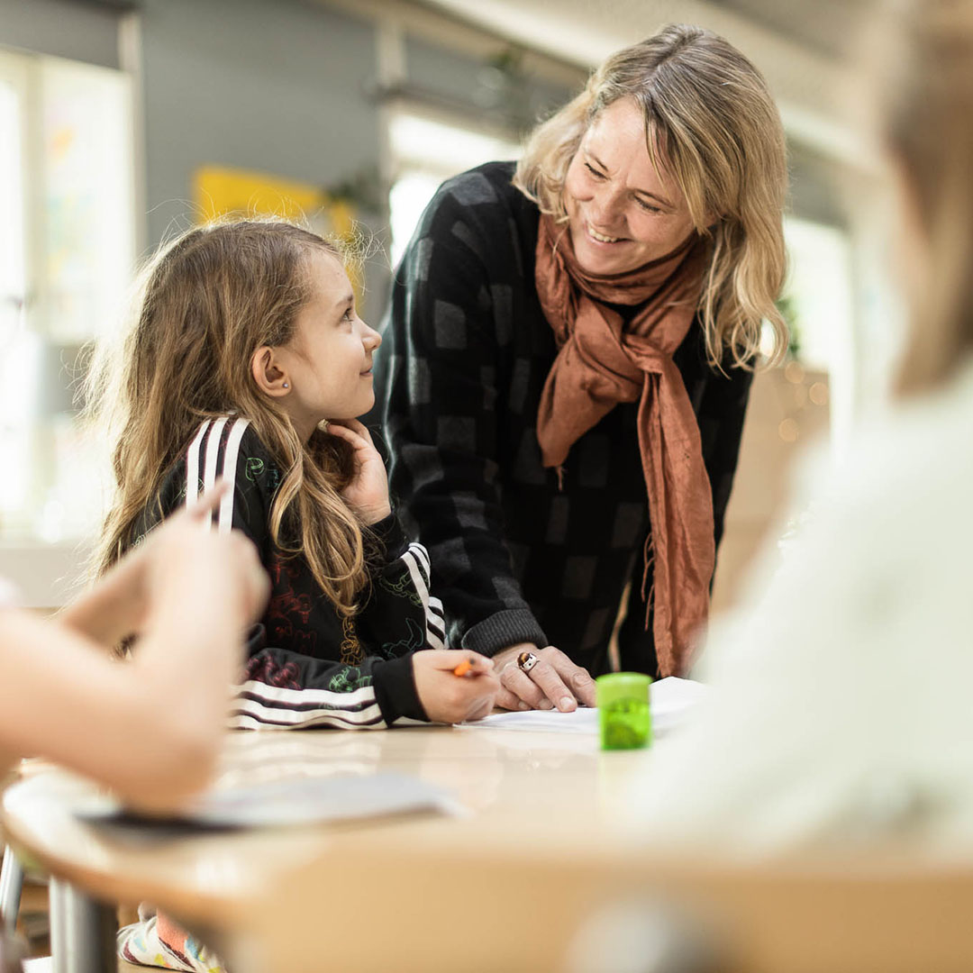 Pedagog står och hjälper elever med skolarbete