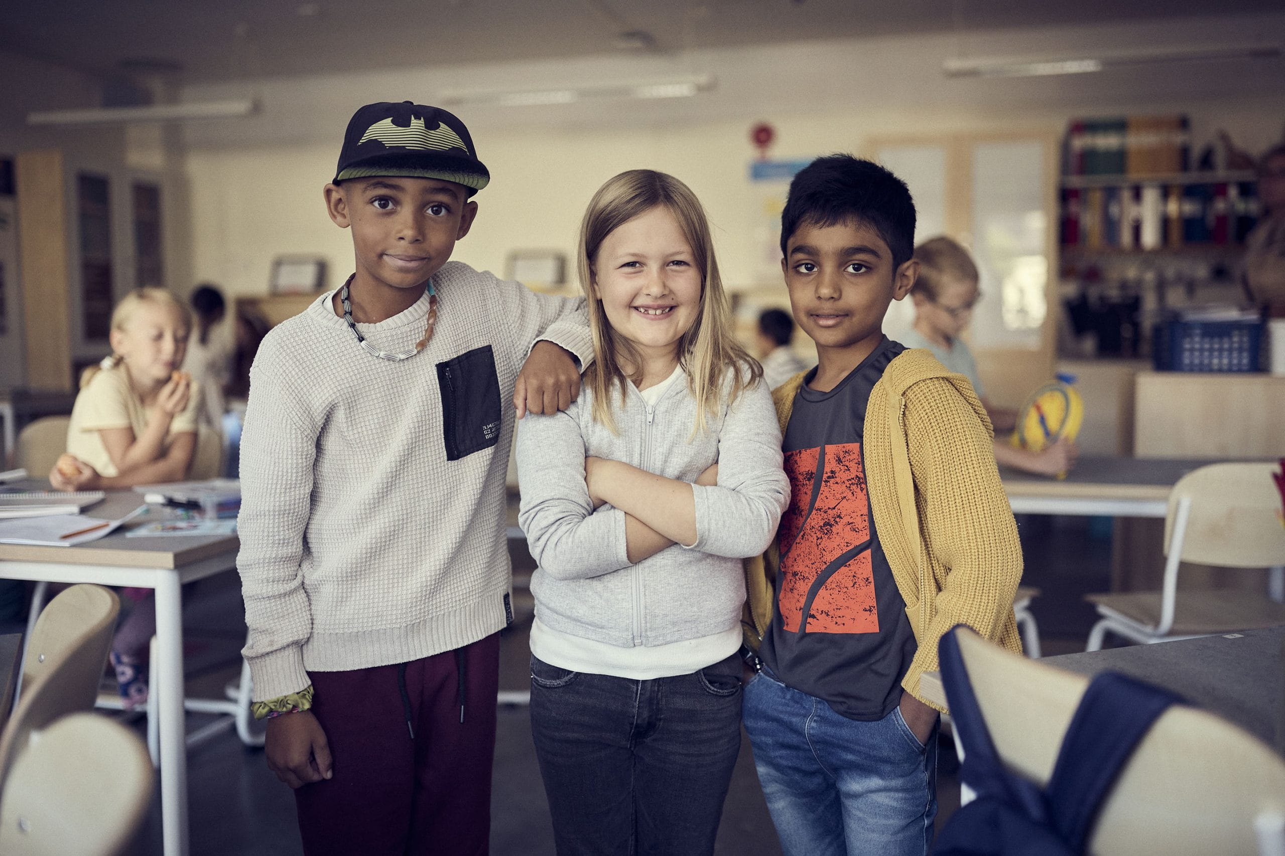 Tre elever står bredvid varandra i ett klassrum på Montessori Mondial.
