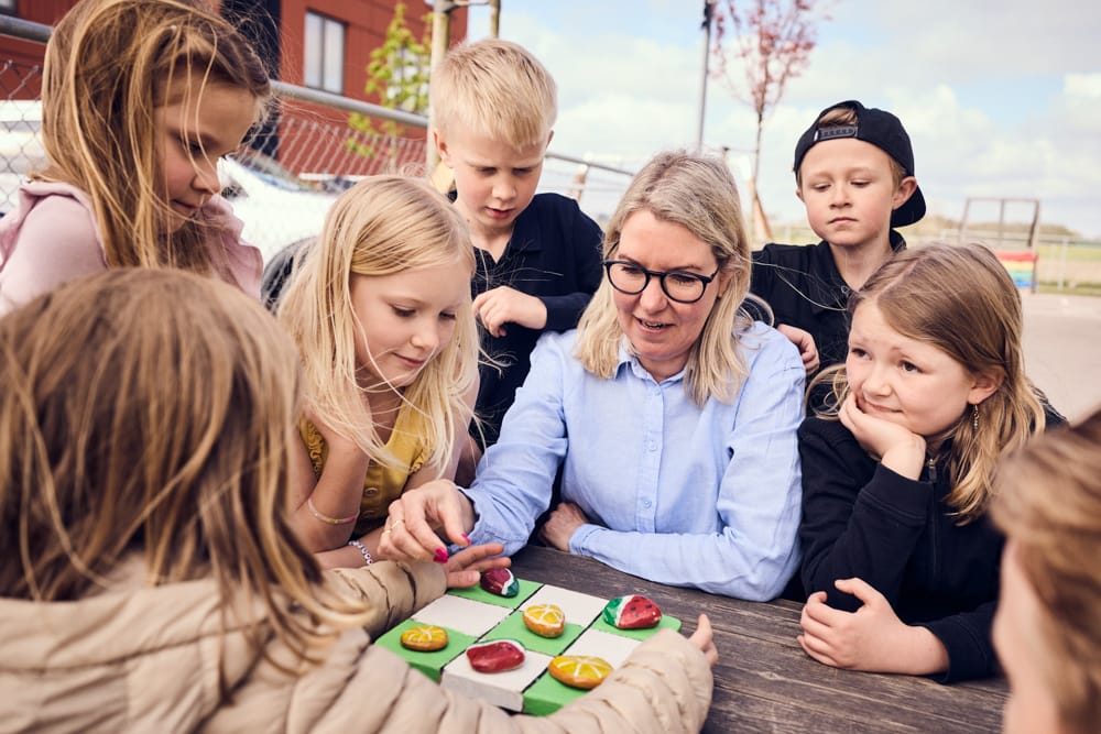 Flera elever och en pedagog spelar spel utomhus.