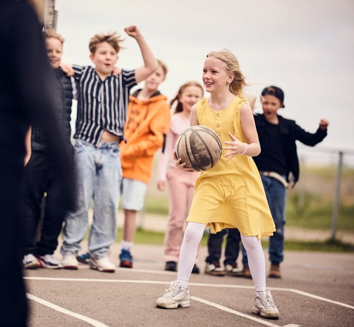 Elever spelar basket på skolgården.