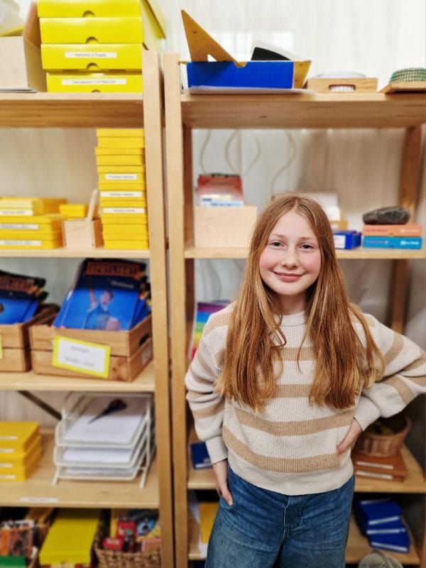 Elev på Montessori Mondial Sandskogen står vid bokhylla i klassrum.