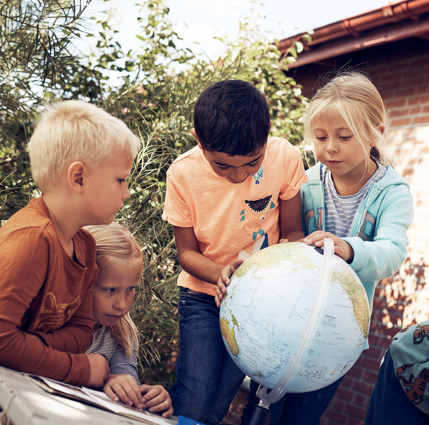 Fyra elever på Montessori Mondial tittar på en jordglob.