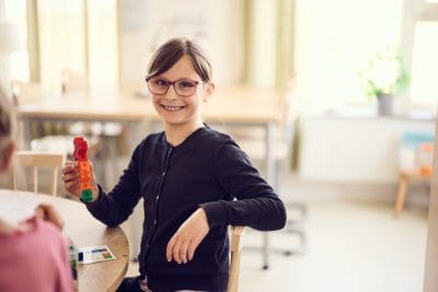 Elev i förskoleklass sitter vid skolbänk.