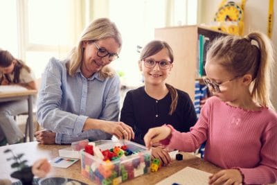 Två elever i förskoleklass lär med klossar och pedagogens stöttning.