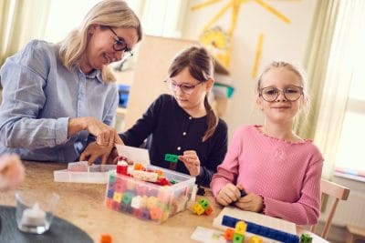 Två elever lär med hjälp av klossar tillsammans med pedagog.