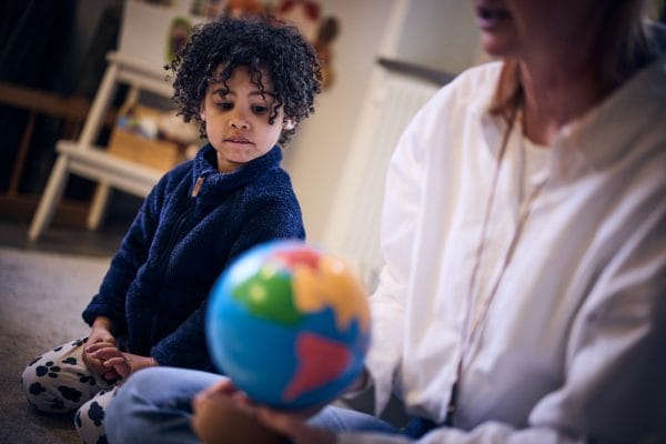 Förskoleelev på Montessori Mondials förskola tittar på en jordglob.