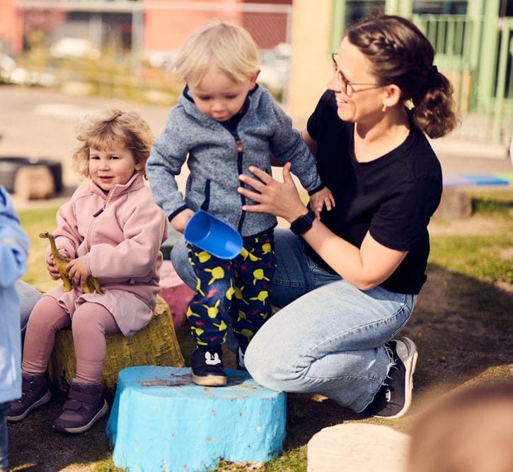 Pedagog och förskolebarn leker utomhus.