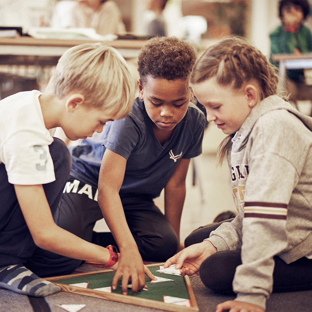 Elever som sitter på golvet och lär sig med hjälp av Montessori-pedagogik