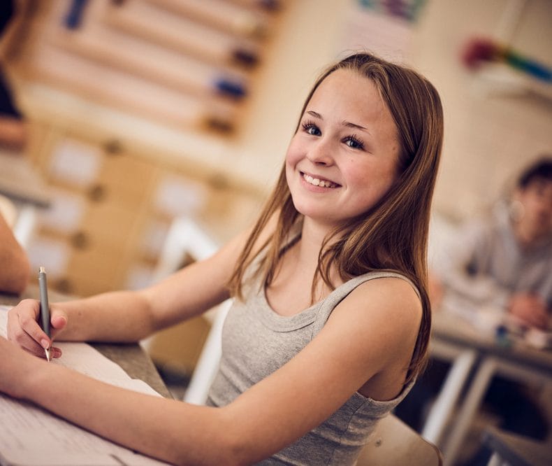 Elev i högstadiet skriver i lärobok.