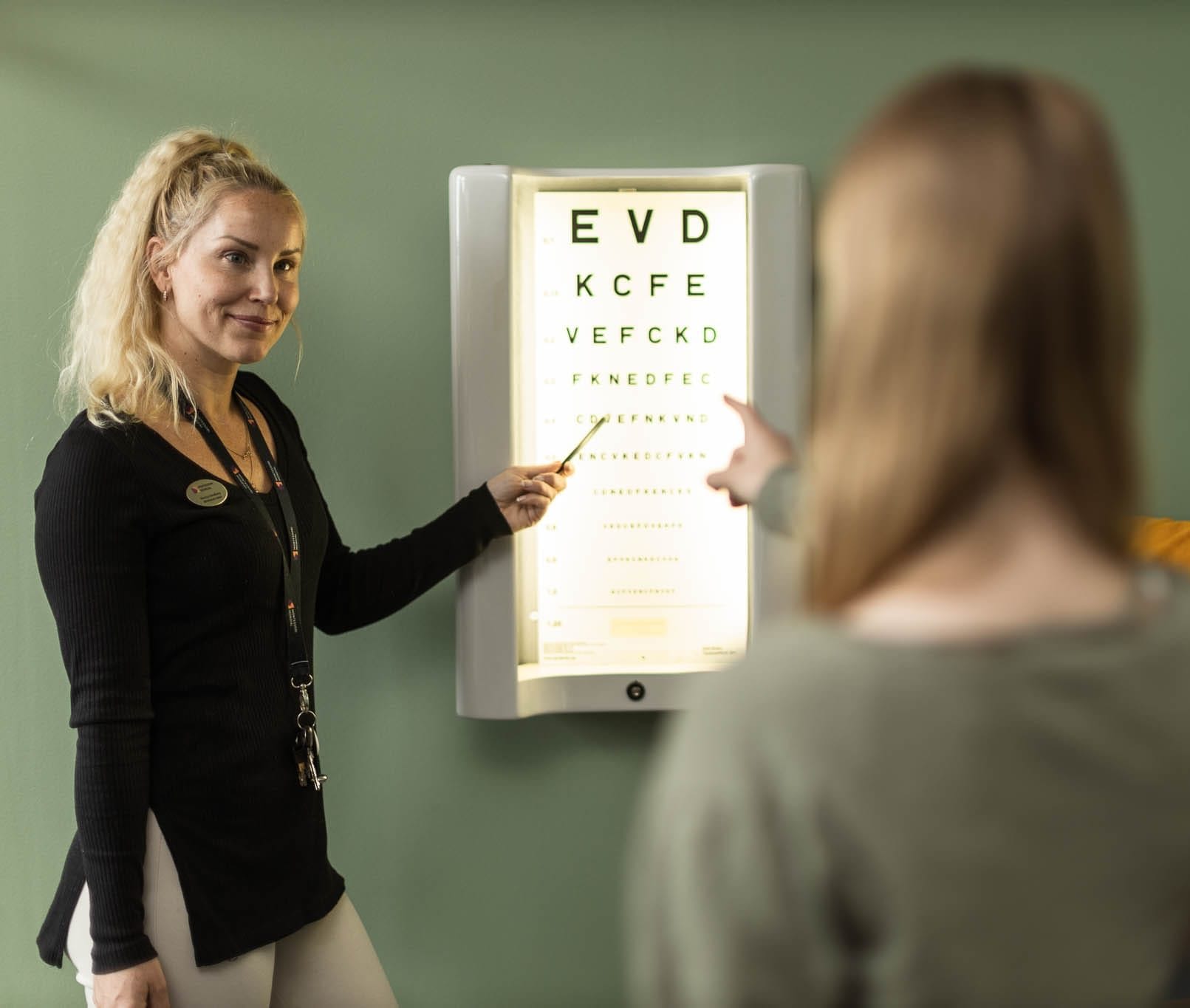 Skolsköterska pekar på syntavla.