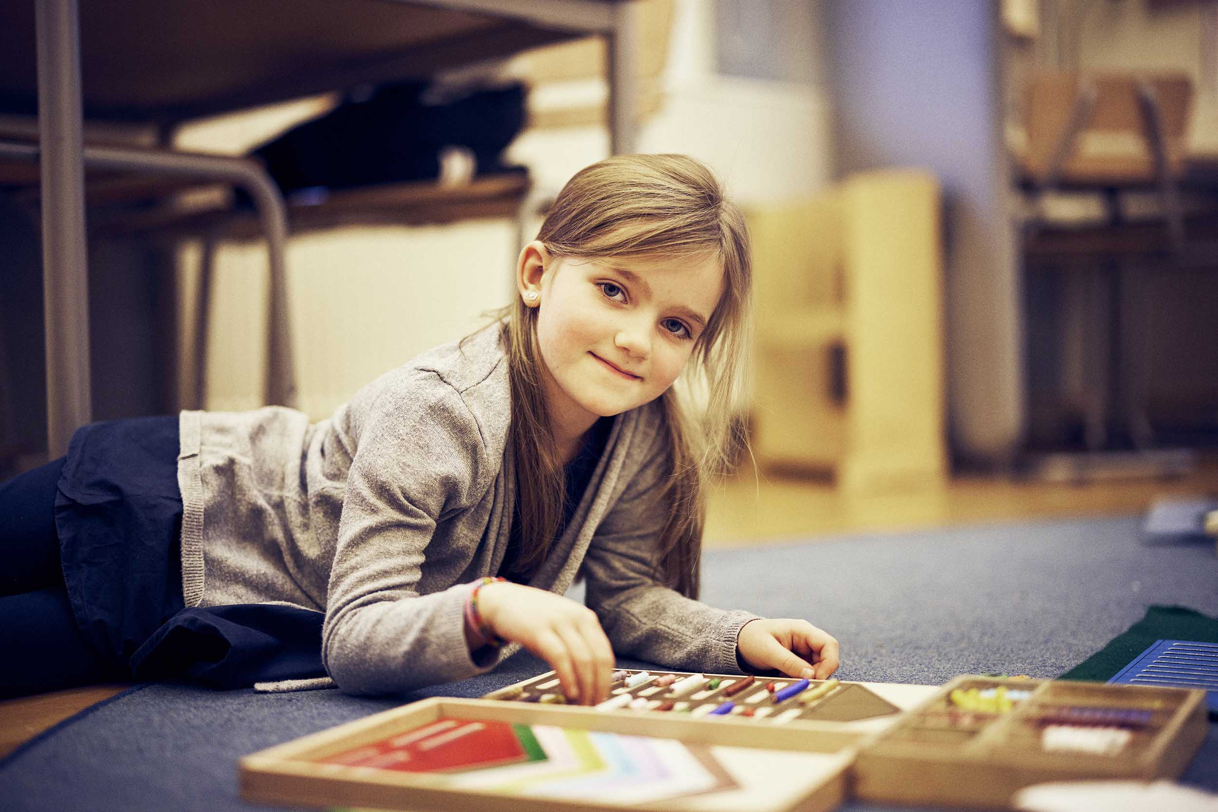 Elev på Montessori Mondial ligger på golvet och arbetar med montessorimaterial.