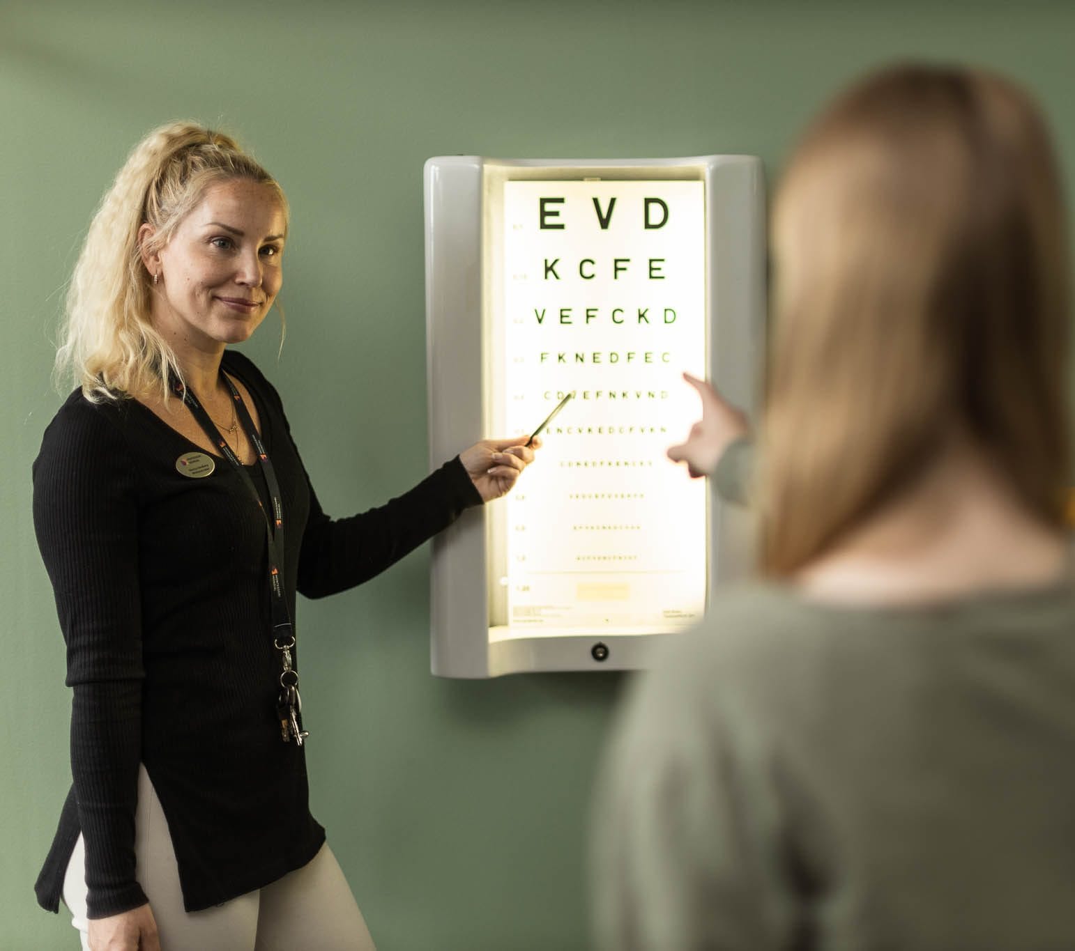 Skolsköterska pekar på syntavla.