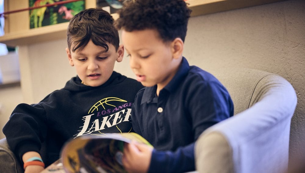 Två elever i förskoleklass läser bok tillsammans.