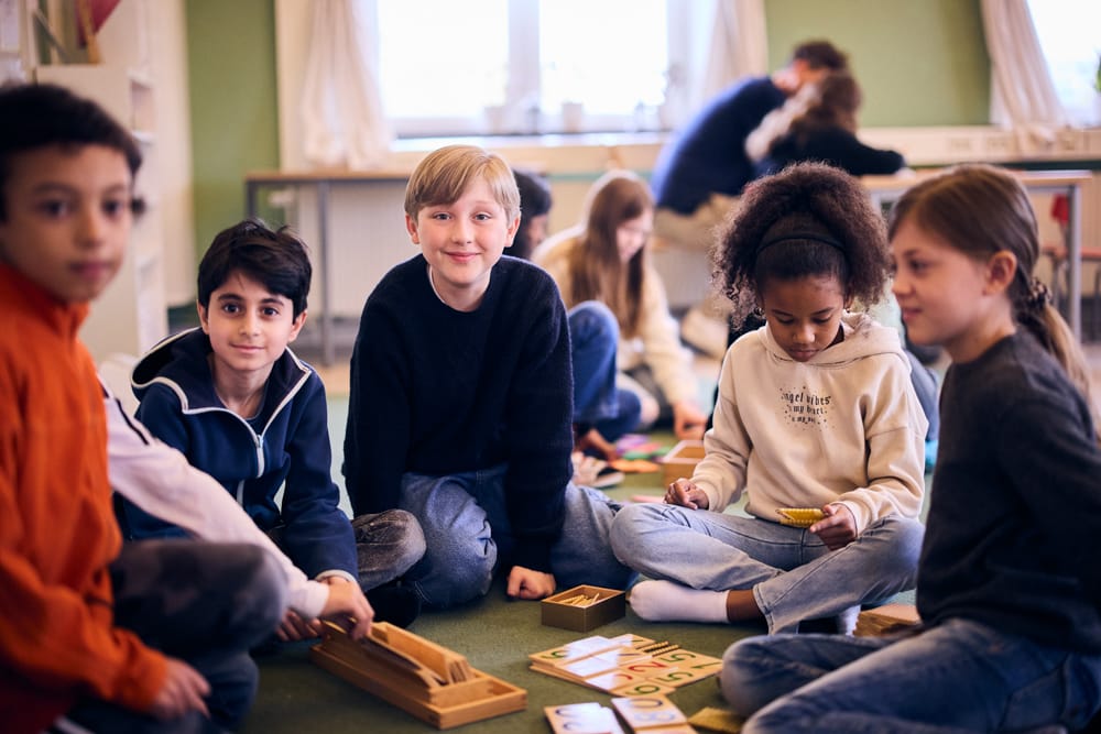 Elever på Montessori Mondial Kungsholmen sitter på golvet och lär.