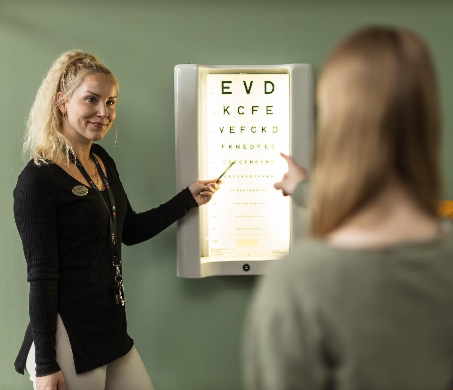 Skolsköterska pekar på syntavla.