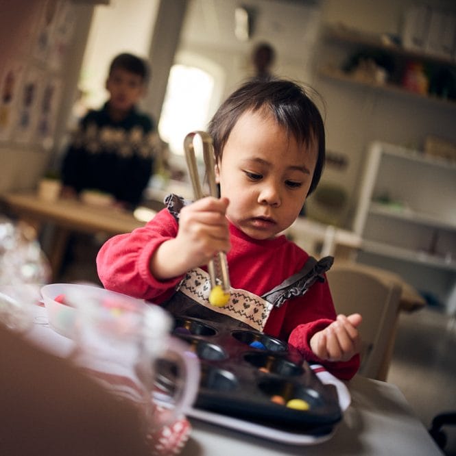 Förskolebarn övar på att greppa med pincett.