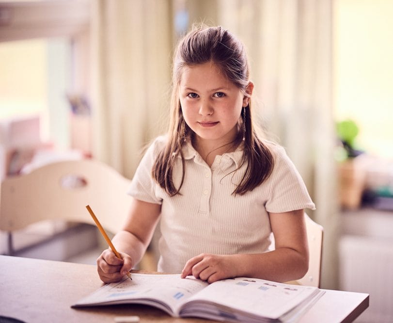 Elev i förskoleklass skriver i lärobok.