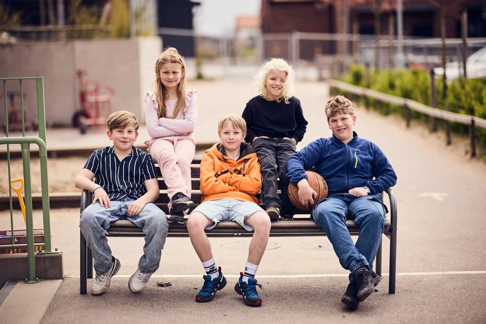 Fem elever sitter på en bänk på skolgården.