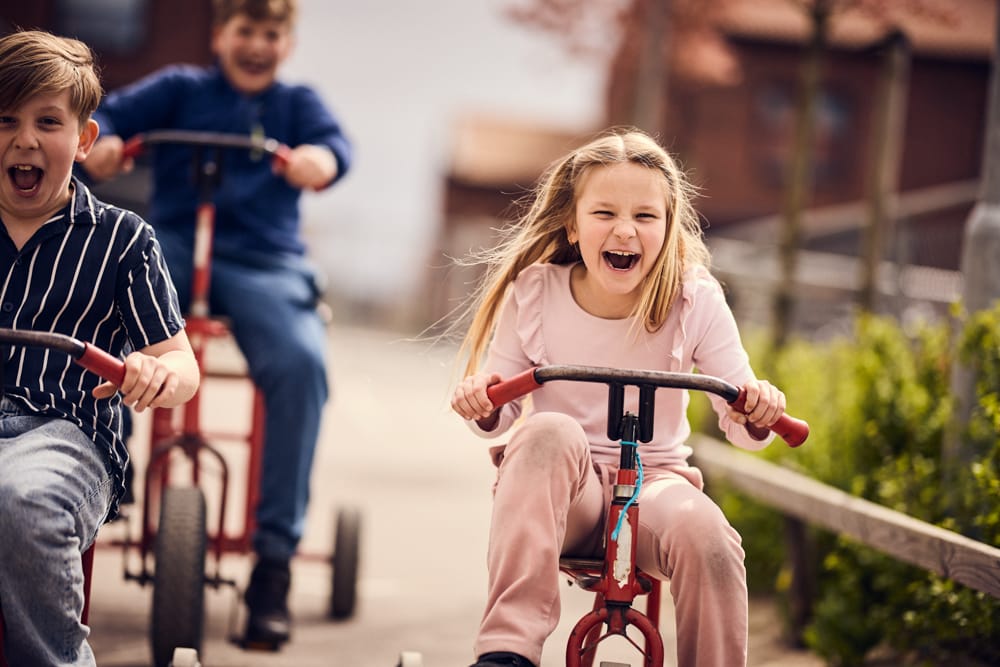 Tre elever cyklar och ropar glatt.