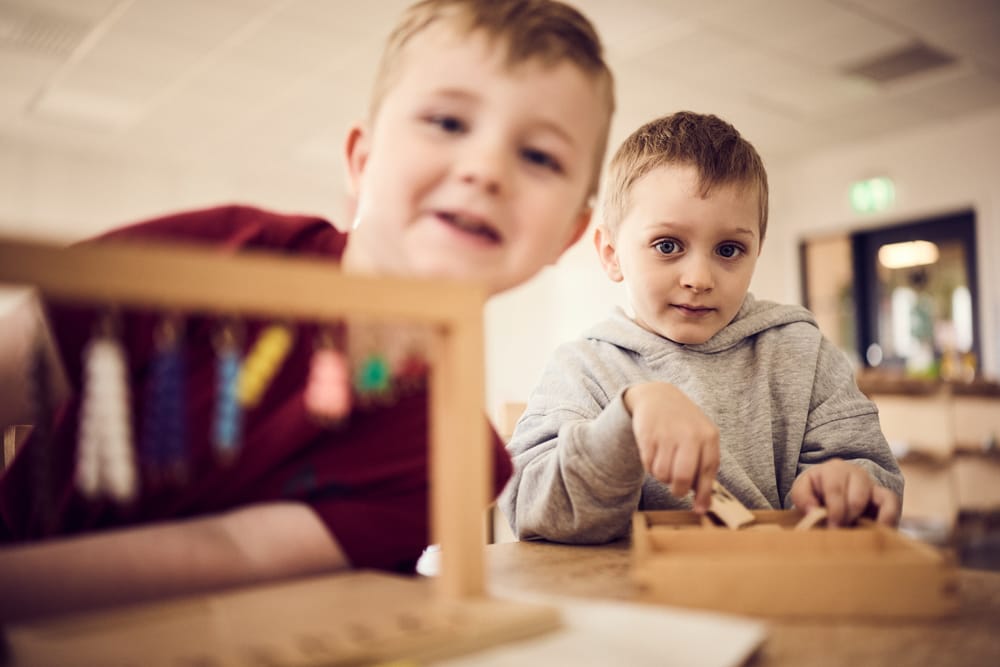 Två förskolebarn lär sig med montessorimaterial.