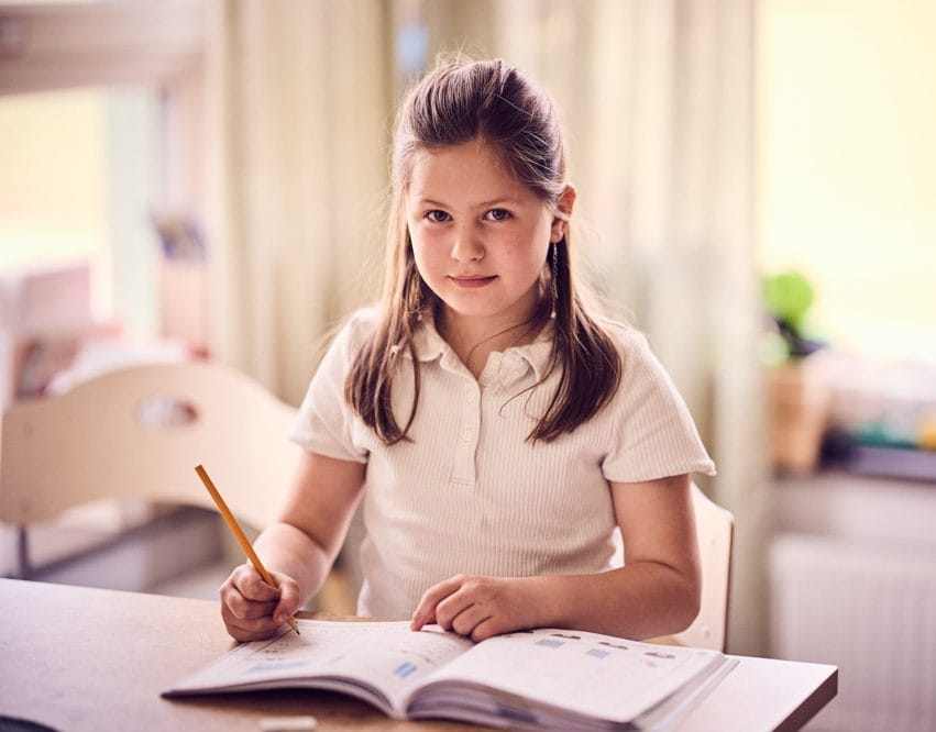 Elev i förskoleklass sitter med lärobok.
