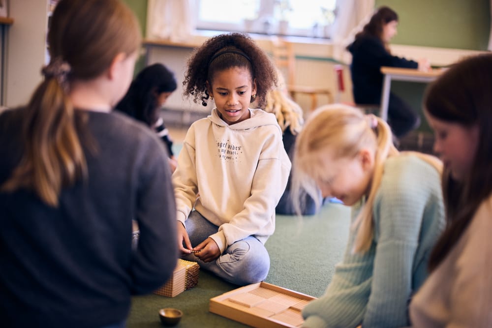 Elever sitter på golvet och lär med montessorimaterial.